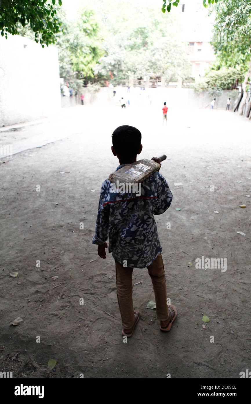 A young Indian boy waits for his turn to bat during a game of street cricket Stock Photo