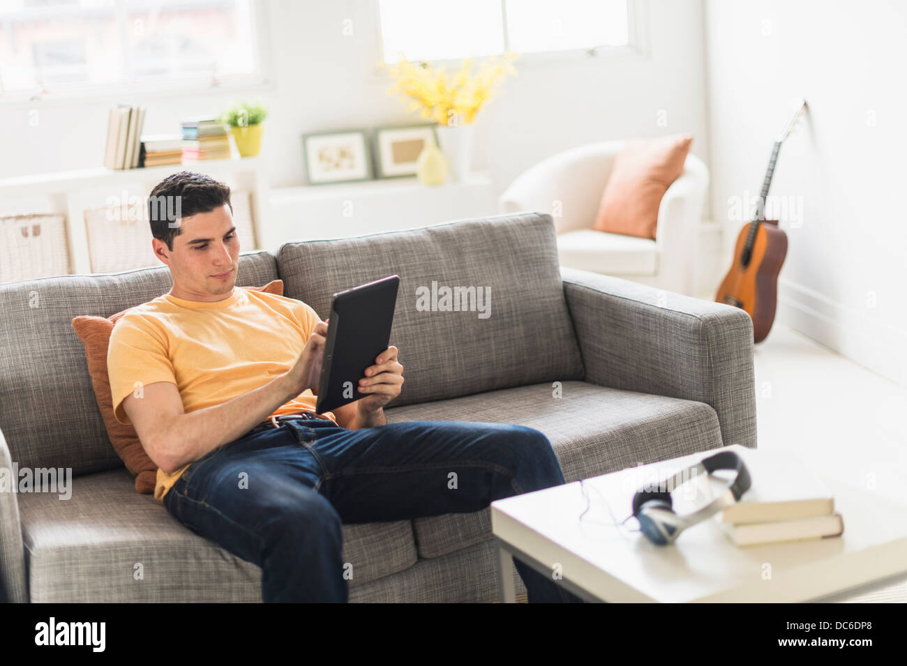 Man sitting on sofa and using digital tablet Stock Photo