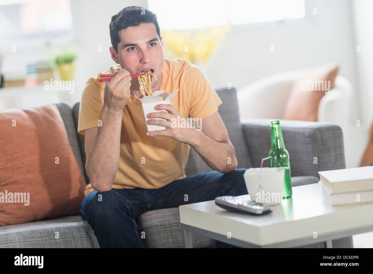 Man eating take out meal and watching television Stock Photo