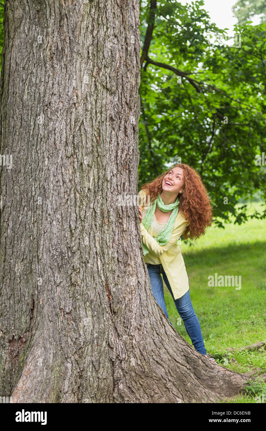 Woman leaning on tree in park Stock Photo