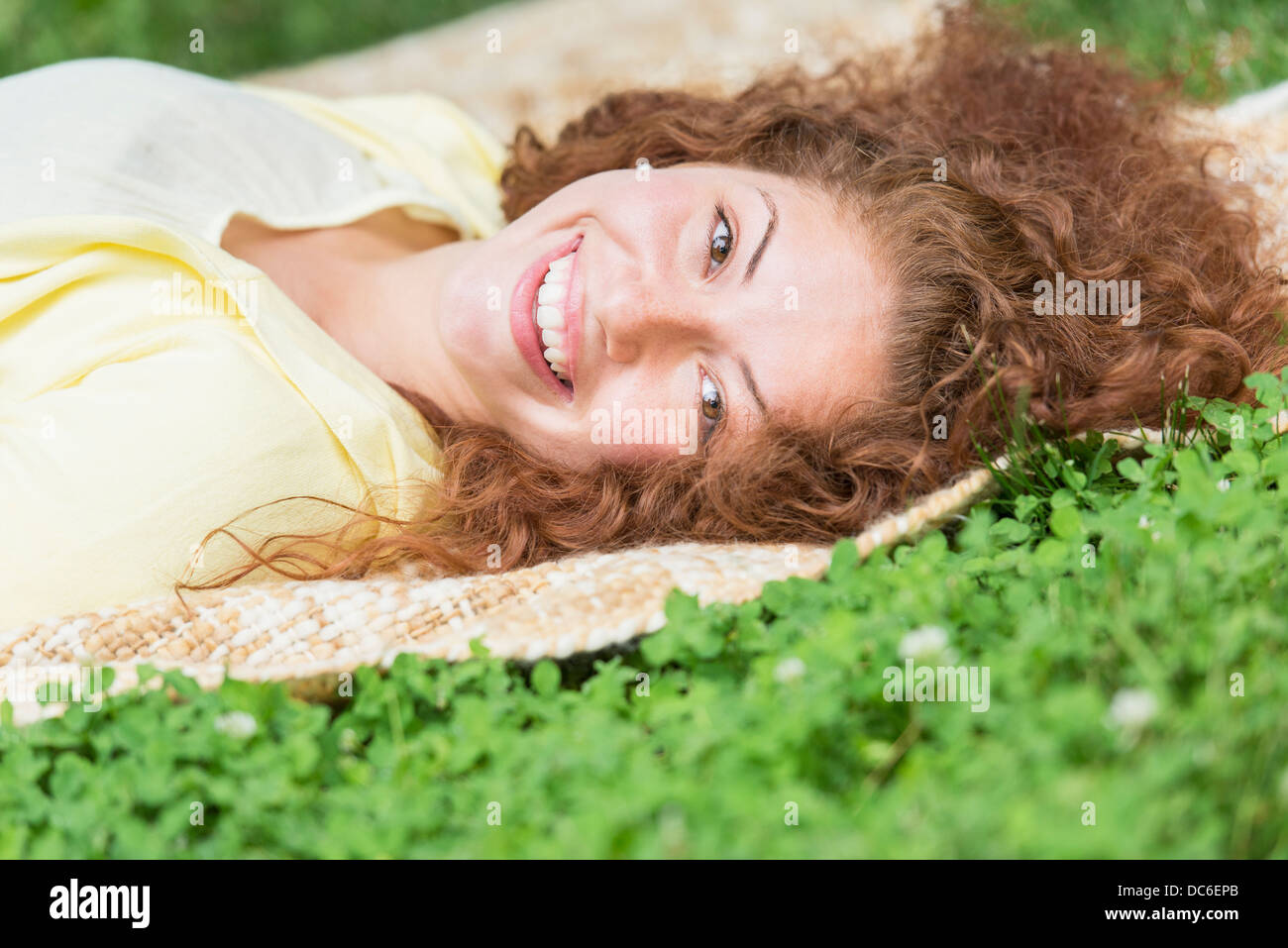 Portrait of young woman lying on grass in park Stock Photo - Alamy