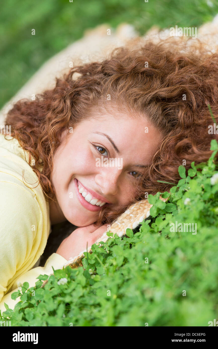 Portrait of young woman lying on grass in park Stock Photo - Alamy
