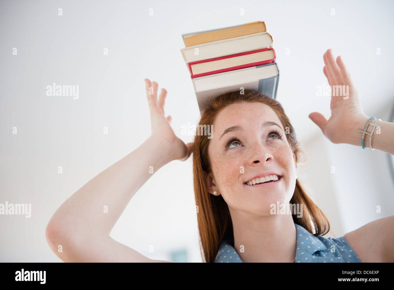 Teenage girl (14-15) holding stack of books on head Stock Photo - Alamy