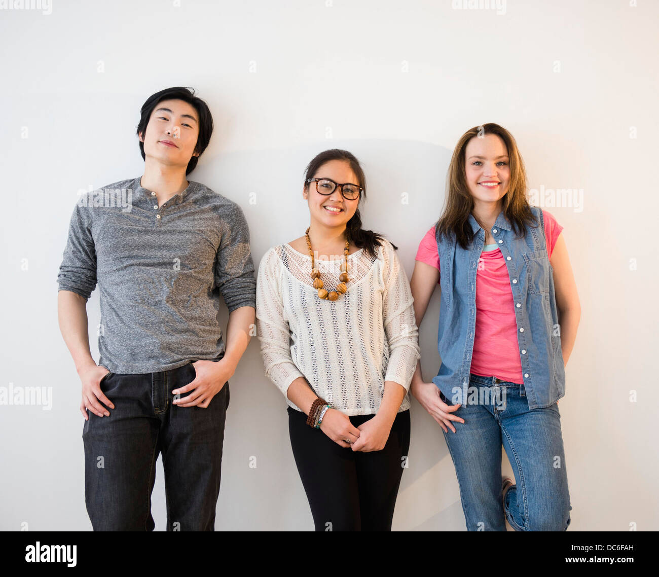 Portrait of young women and man against white wall Stock Photo - Alamy