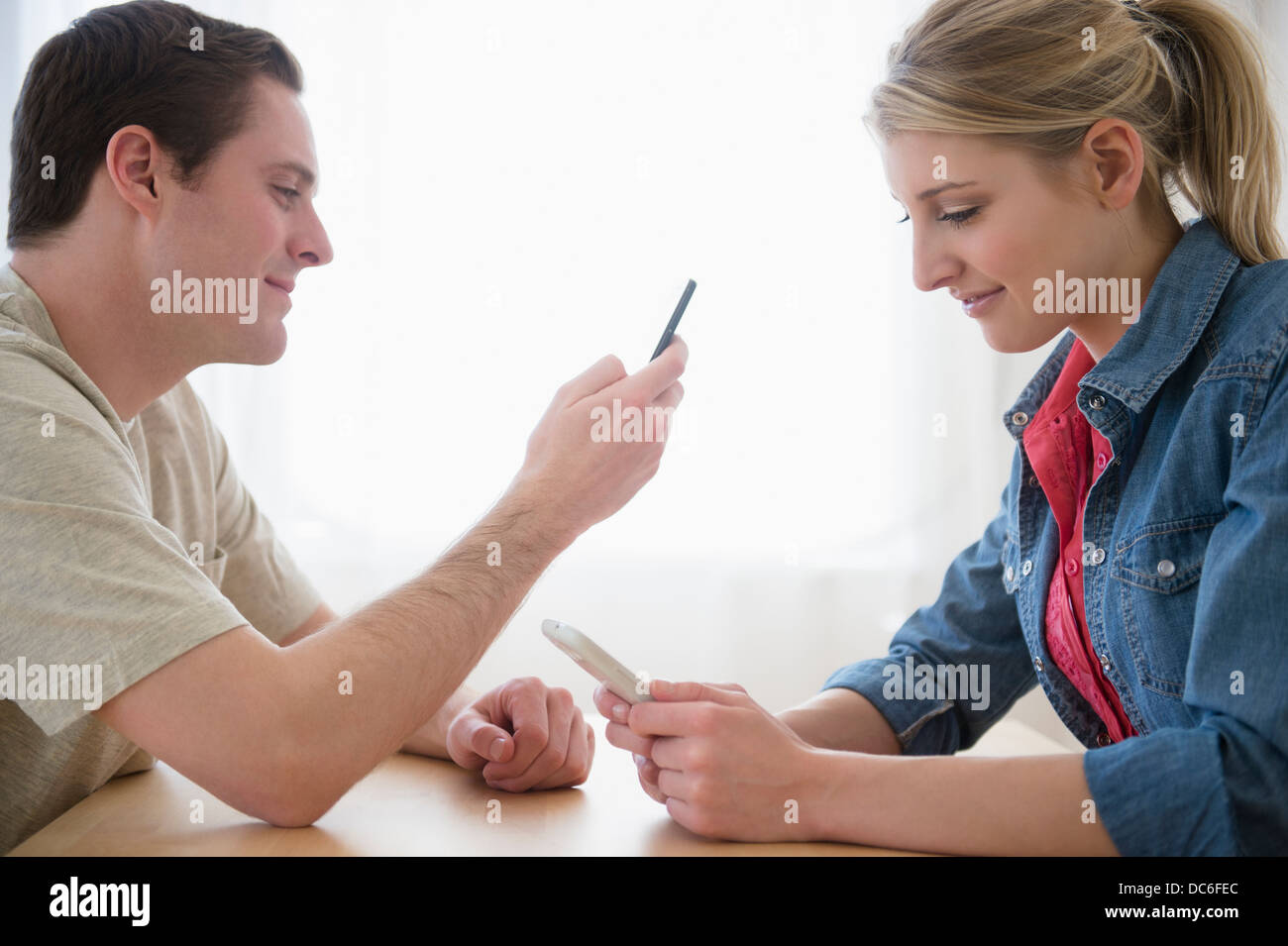 Couple at table using smartphones Stock Photo