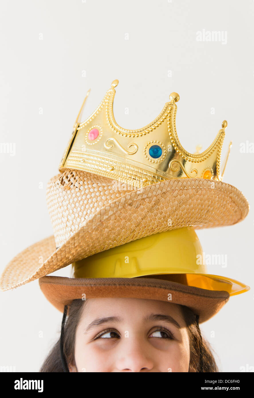 Girl (8-9) wearing stack of hats and crow on head Stock Photo