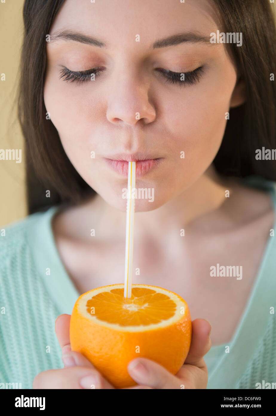 Young woman drinking orange juice from orange fruit Stock Photo Alamy