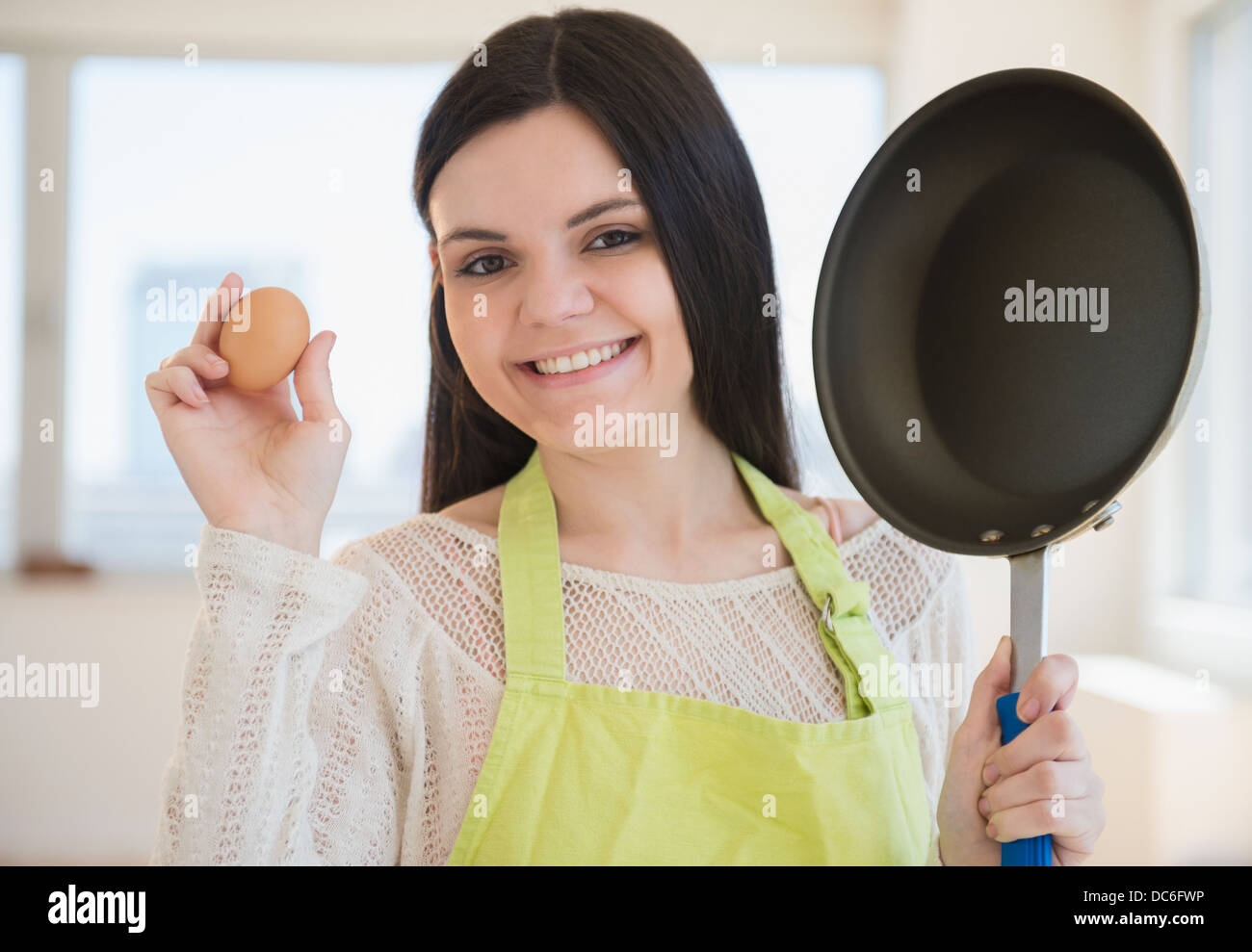 https://c8.alamy.com/comp/DC6FWP/young-woman-holding-frying-pan-and-egg-DC6FWP.jpg