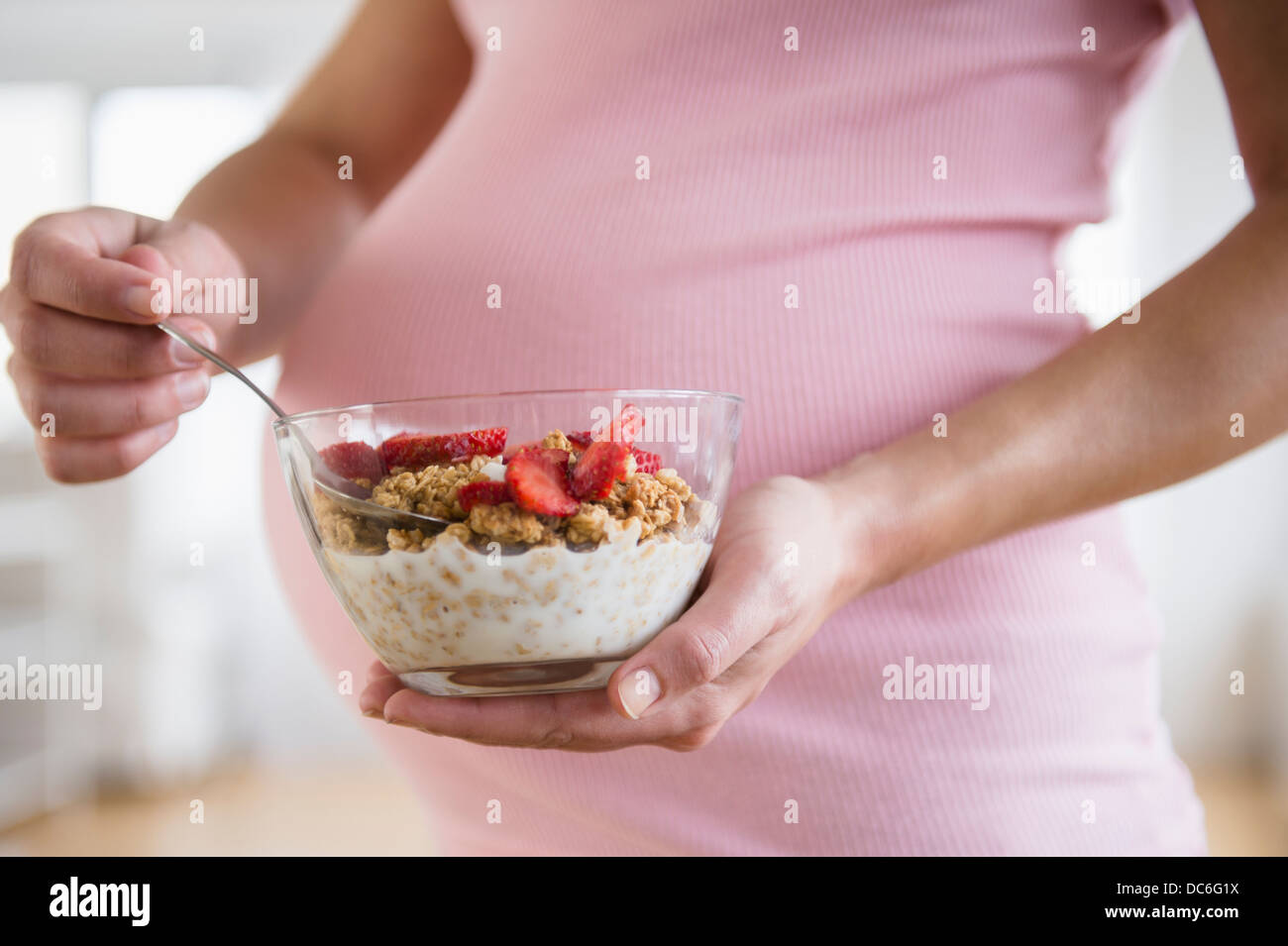 Mid section of pregnant woman holding bowl with granola Stock Photo