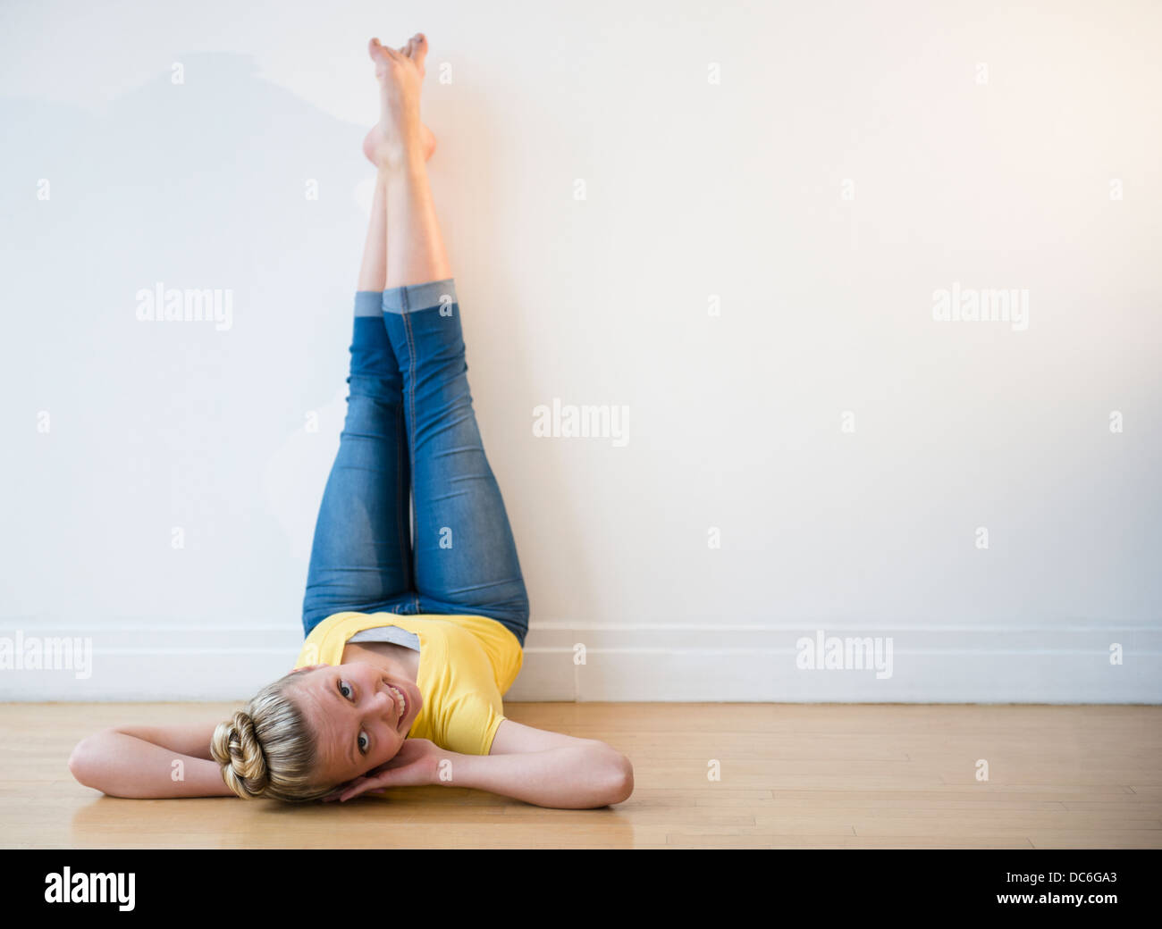 Portrait of teenage (16-17) ballerina lying down with feet up against wall Stock Photo