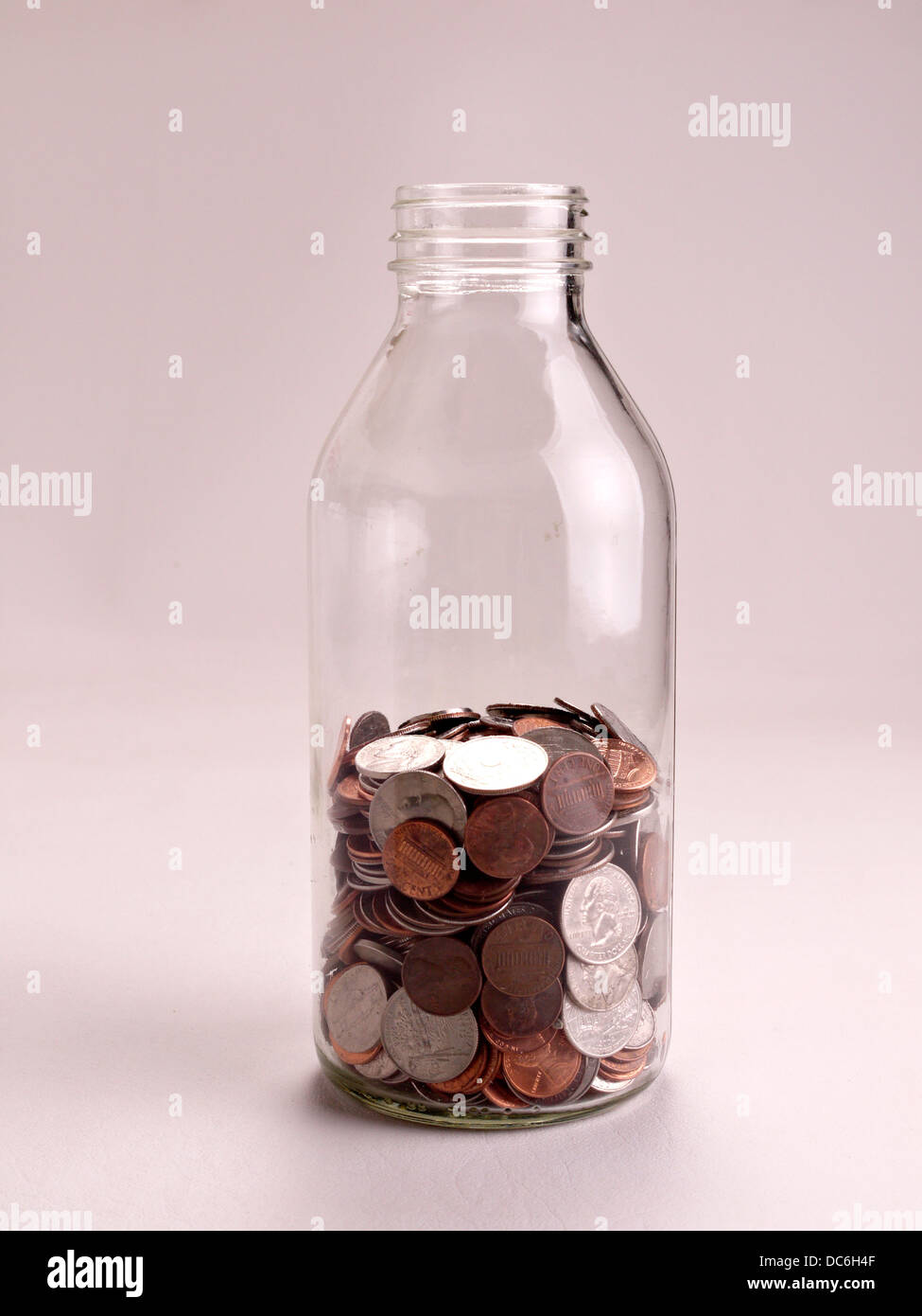 A half full jar of American coins sits on a white background. Stock Photo