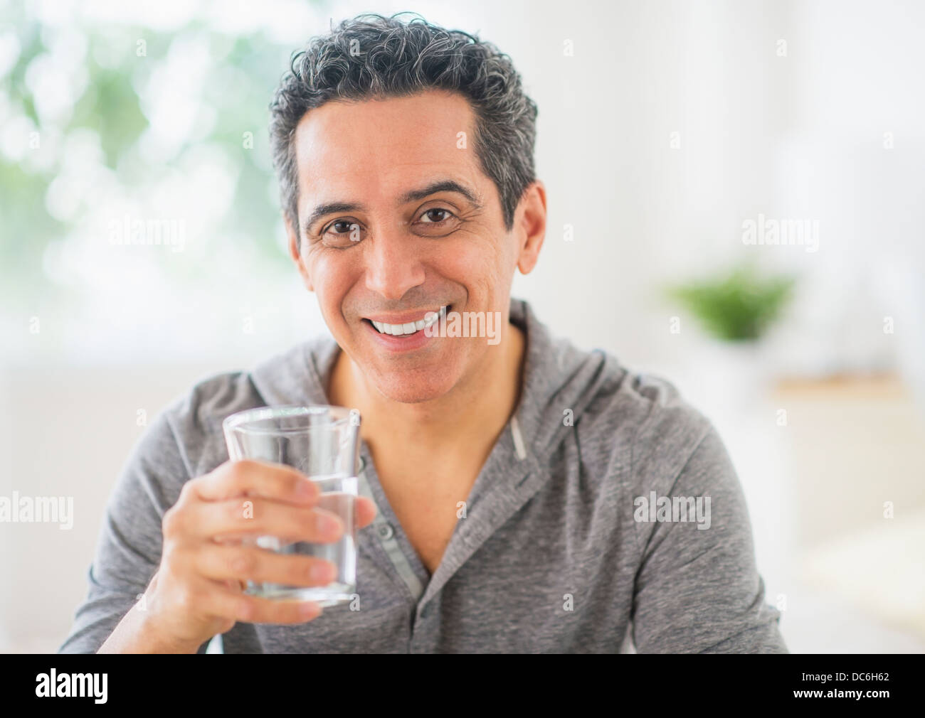 Happy Man Holding Drinking Glasses In The Kitchen High-Res Stock