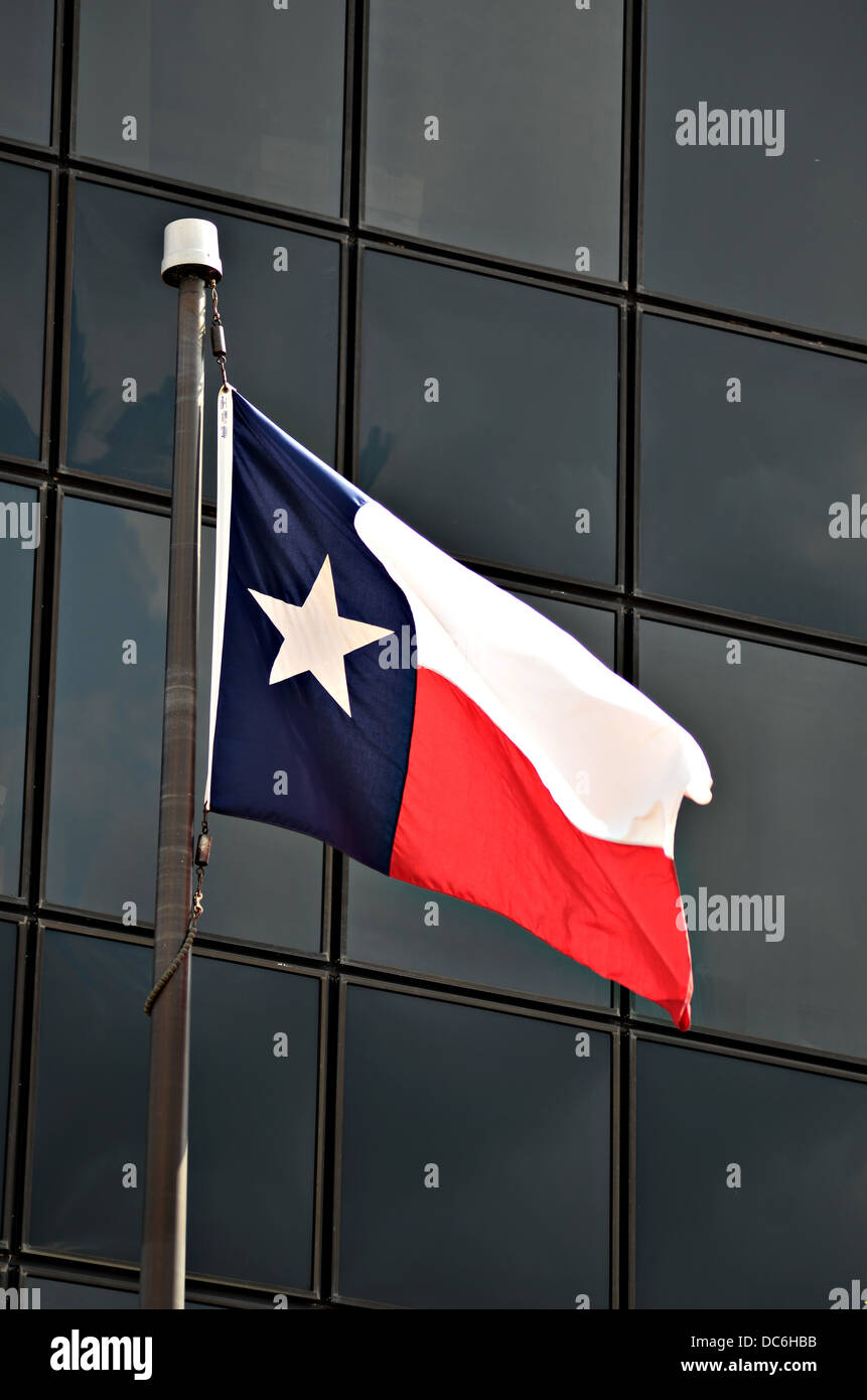 A Texas state flag is blowing in the wind outside a office building in downtown Tyler Texas. Stock Photo