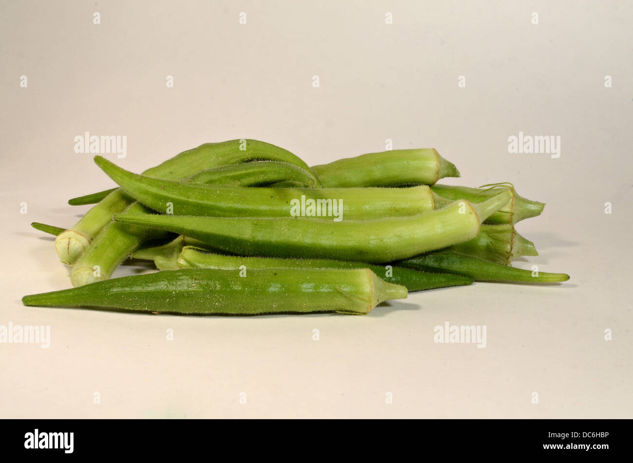 A small pile of okra is laying on a white background awaiting to be fixed for dinner. Stock Photo