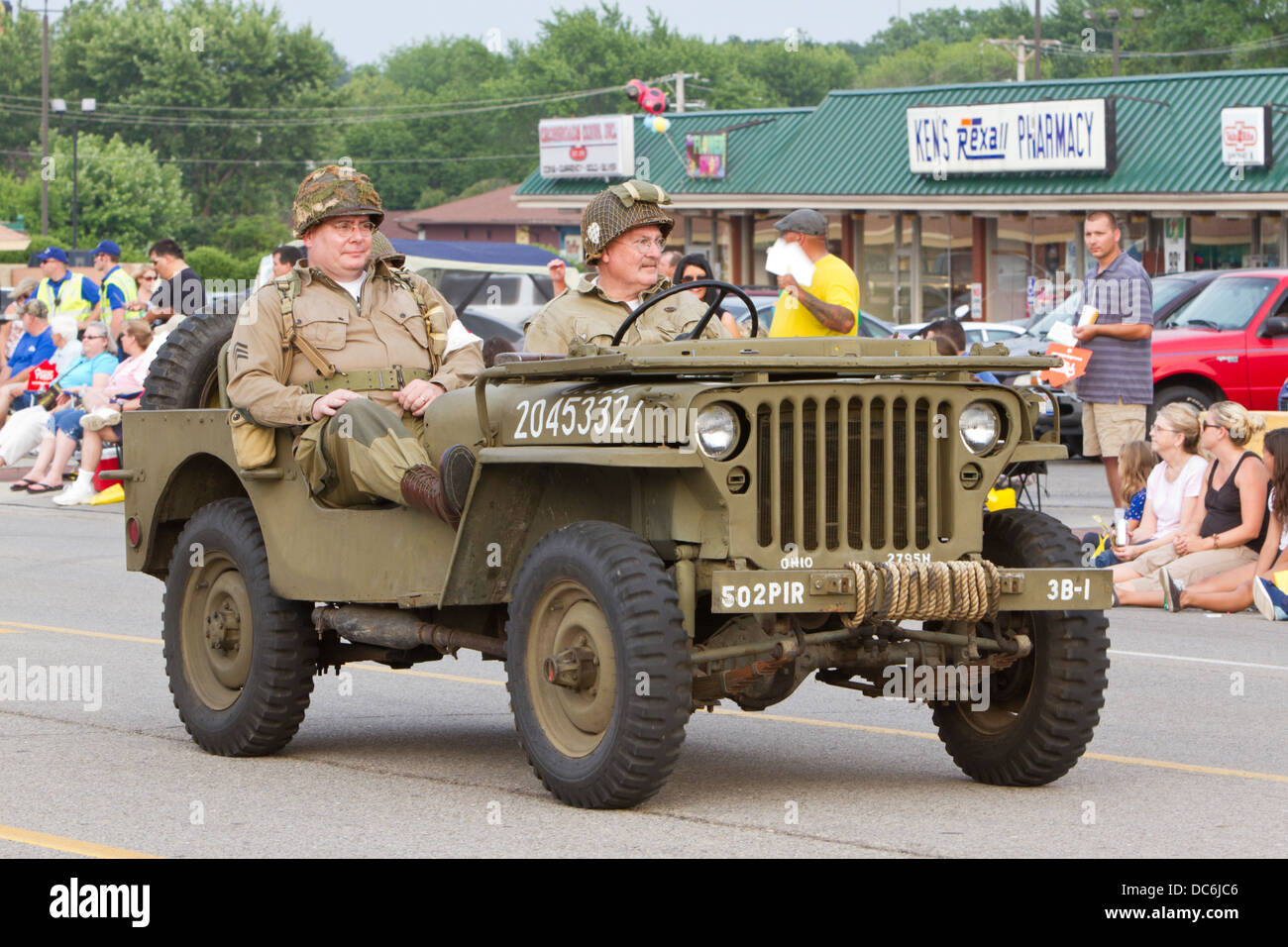 Two men dressed as WW2 GIs riding a vintage jeep. Stock Photo