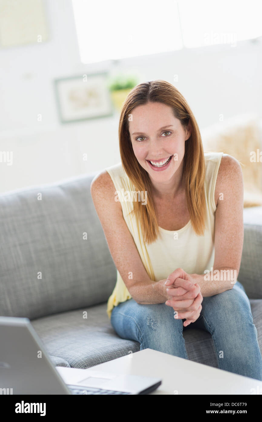Portrait of young woman sitting on sofa Stock Photo - Alamy