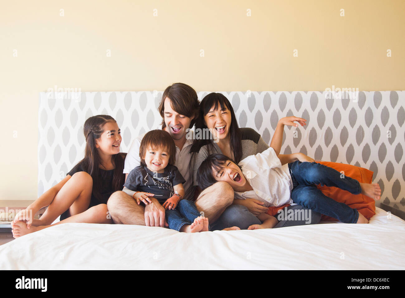 Portrait of family sitting on bed Stock Photo