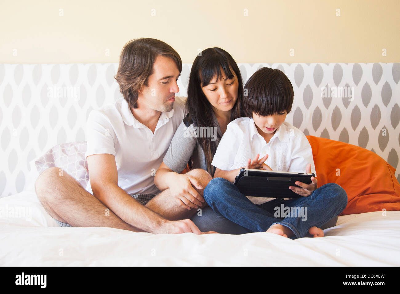 Portrait of family sitting on bed Stock Photo