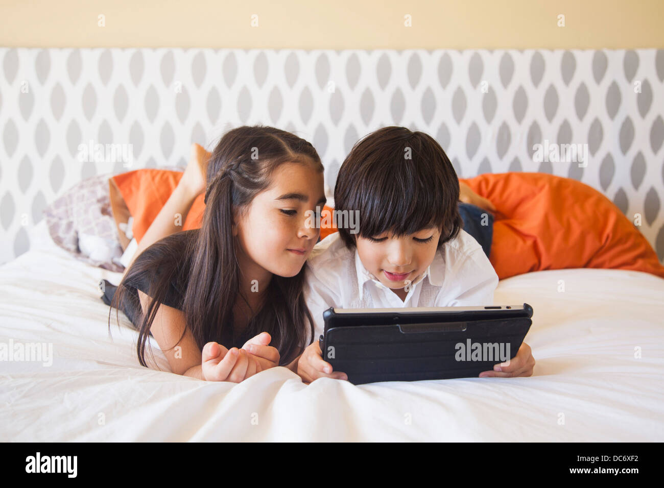 Siblings (8-9) using digital tablet in bedroom Stock Photo