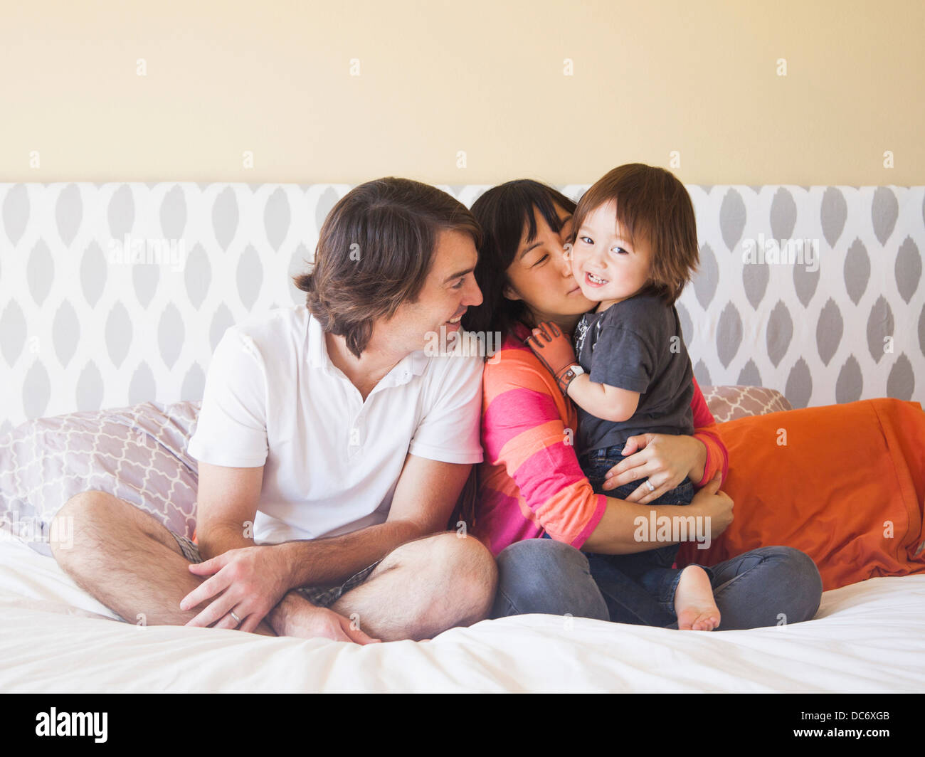 Portrait of couple sitting on bed with son (2-3) Stock Photo