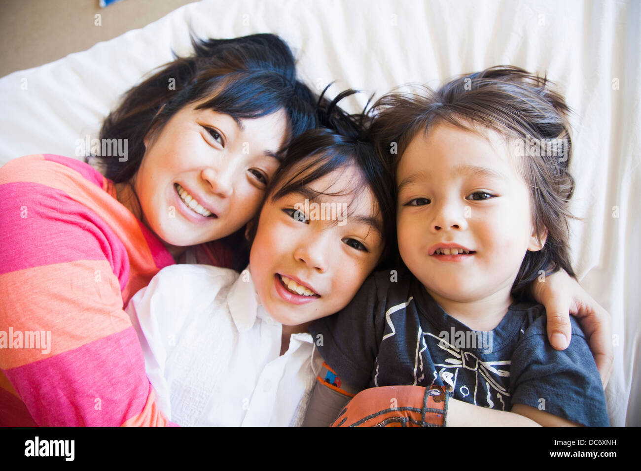 Mother with children cuddling on bed Stock Photo