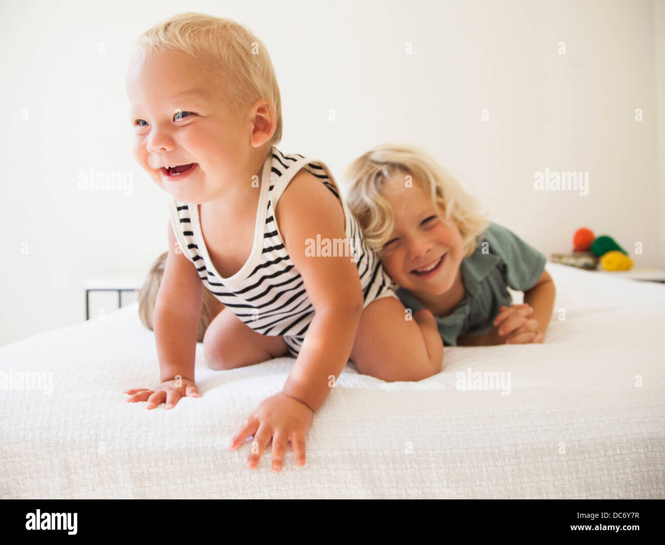 Boy (6-7) and girl (2-3) playing with their baby brother (6-11 months) Stock Photo