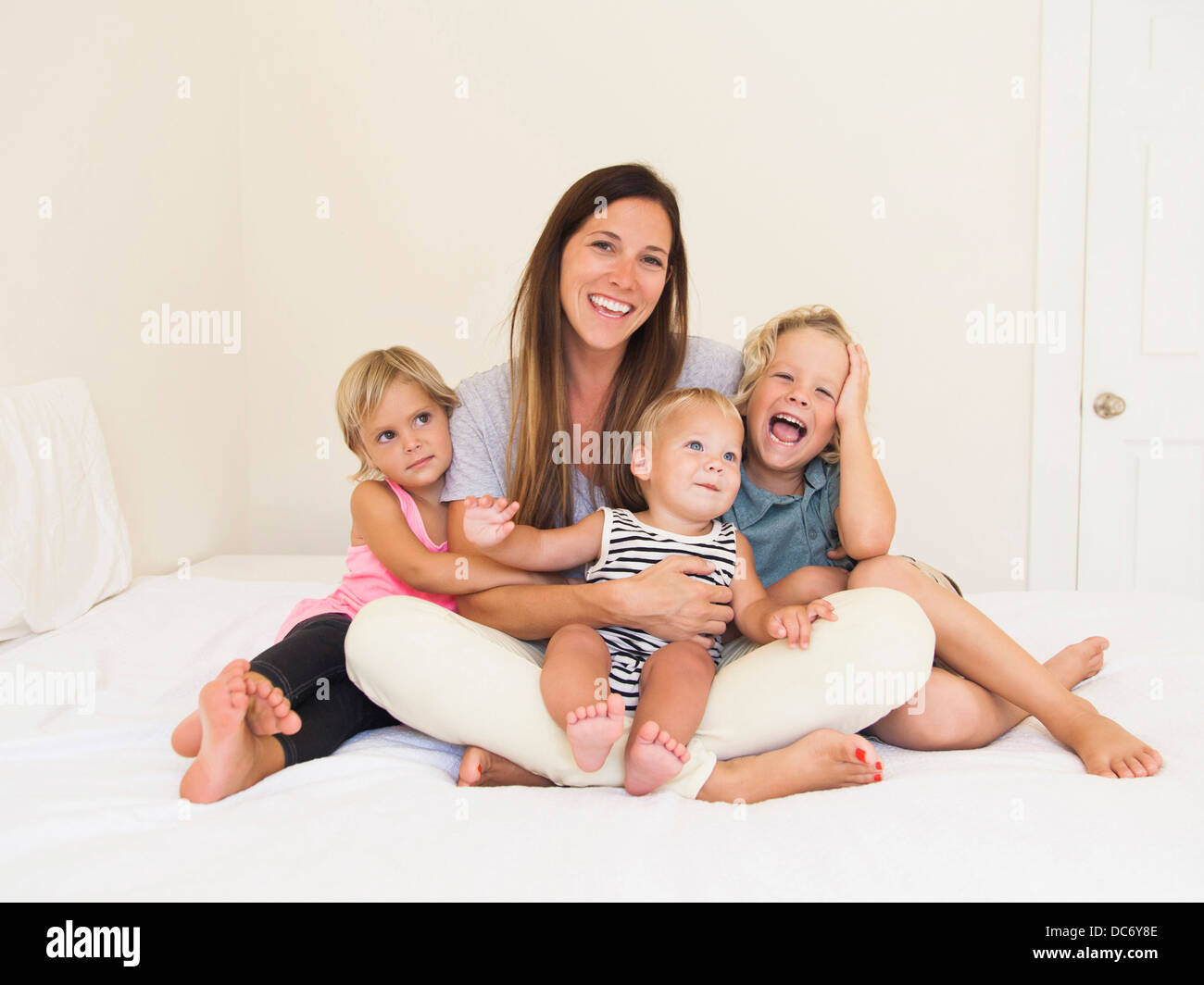 Mother with three kids (6-7, 2-3, 6-11 months) Stock Photo