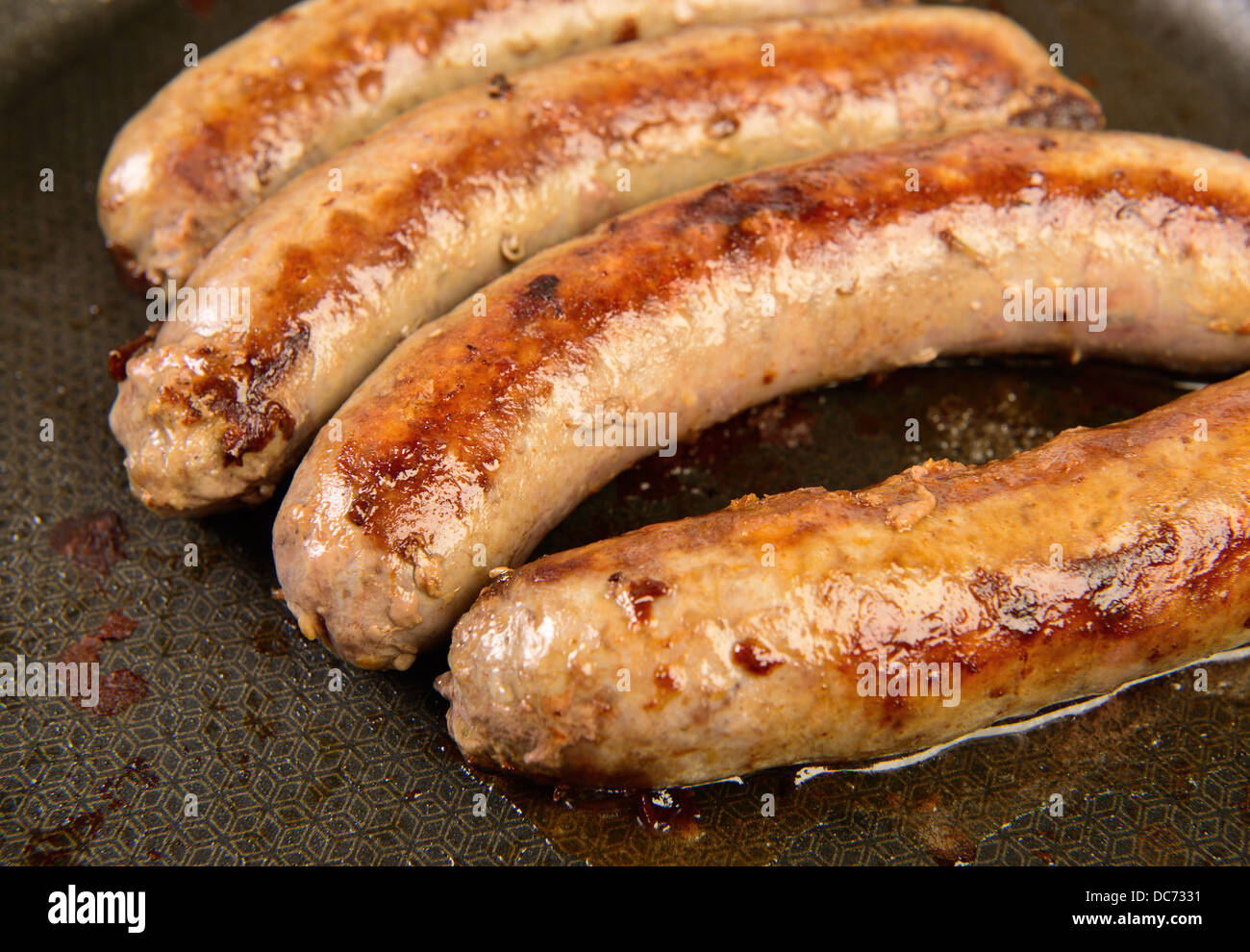 Four beef sausages at frying pan Stock Photo