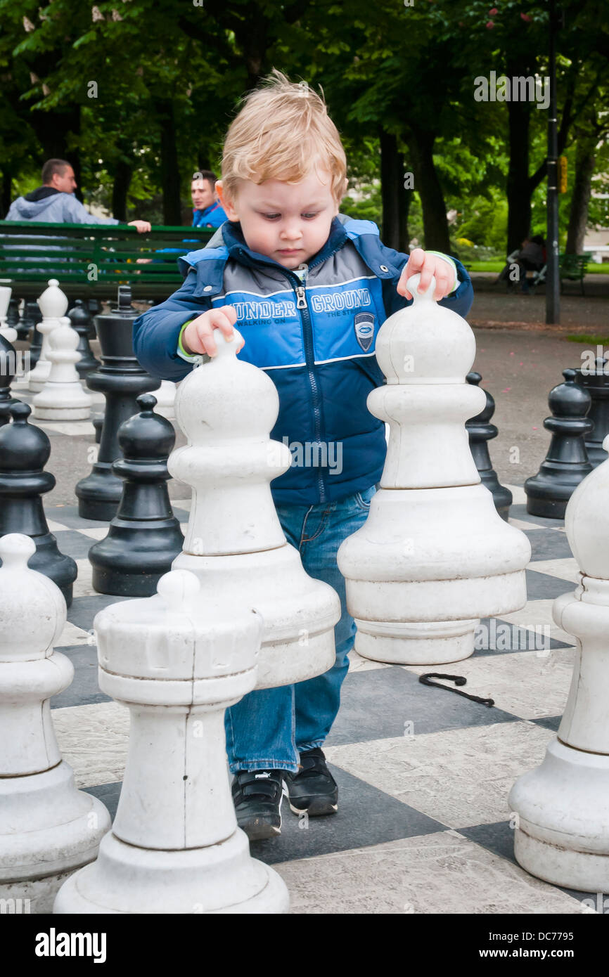 A boy carries two white pawns giant chess pieces in Geneva park, Switzerland, Europe Stock Photo