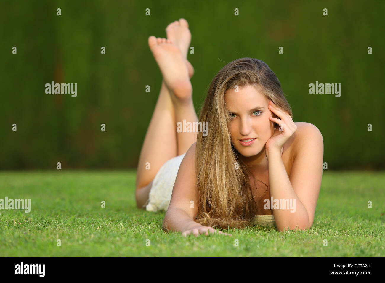 Attractive Sweet Blonde Girl Posing Lying On The Lawn In A Park Looking At Camera Attractive Sweet Blonde Girl Posing Lying On The Lawn In A Park Looking At Camera