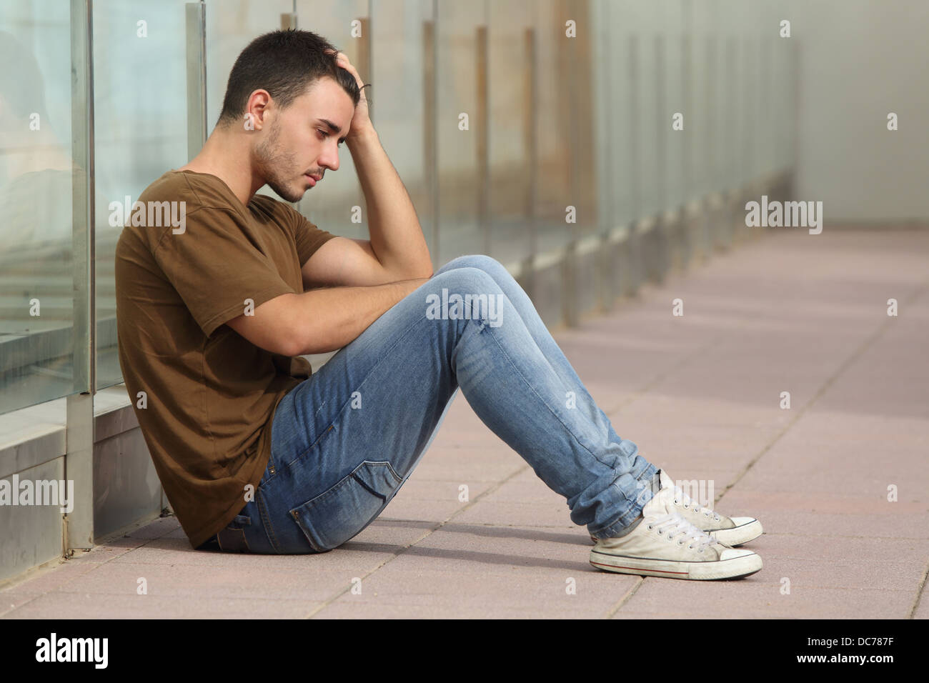 Teenager boy worried sitting on the floor with a hand on the head Stock Photo