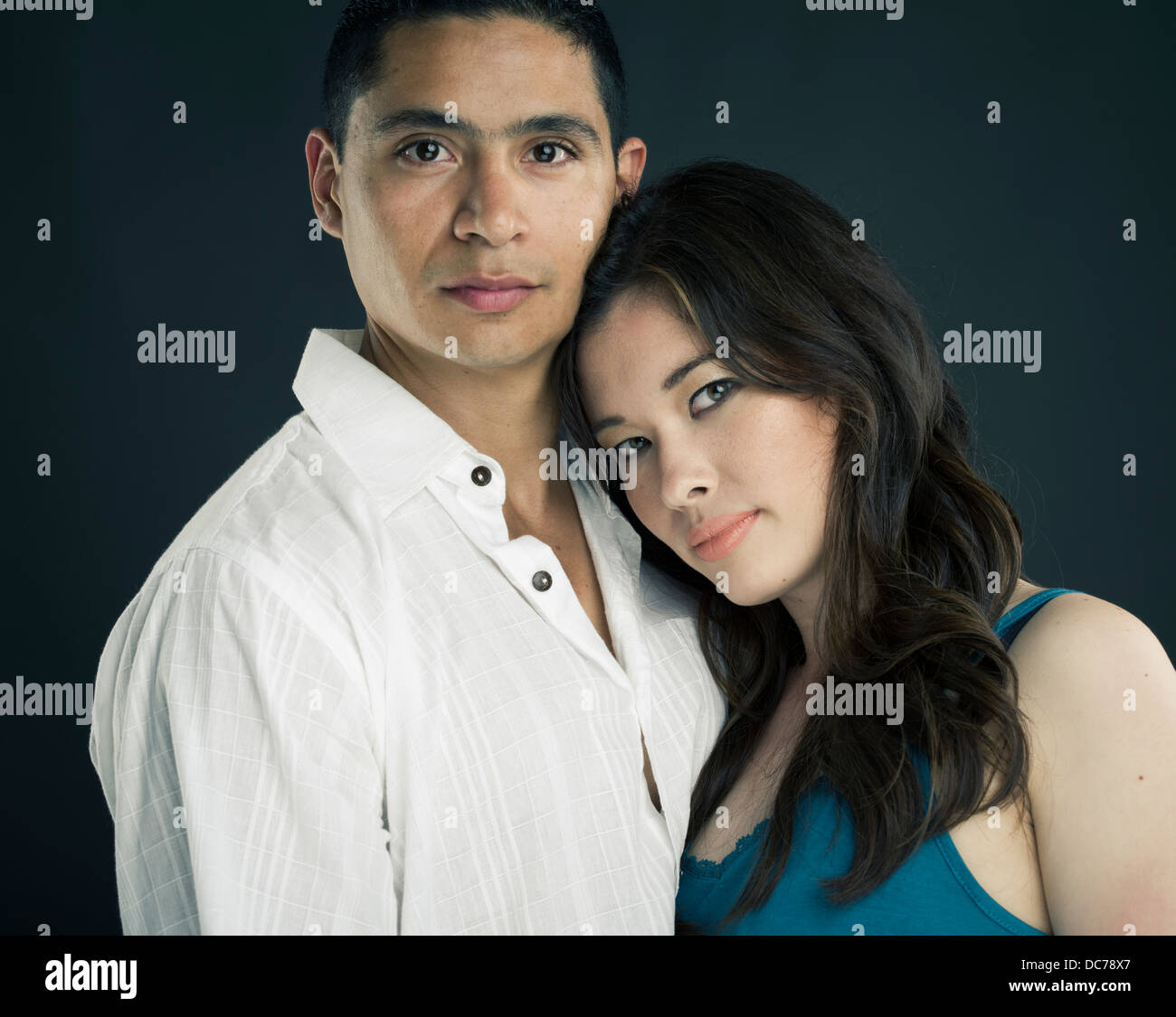 Mixed race Beautiful Couple asian american woman resting head on latino mans chest / shoulder Stock Photo