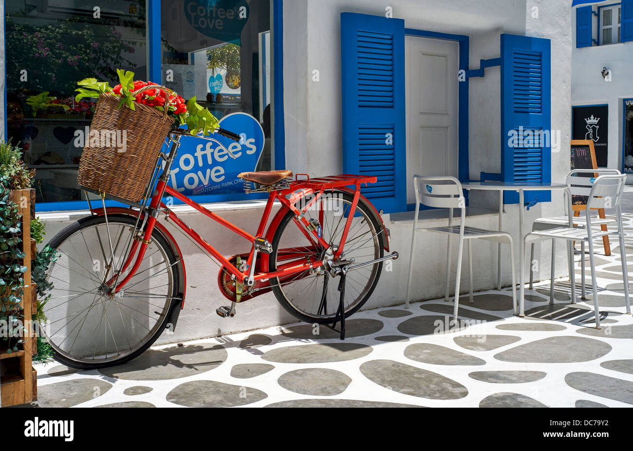 Red bicycle complete with a basket of flowers used as an advertising display for a local coffee shop. Thailand S. E. Asia Stock Photo