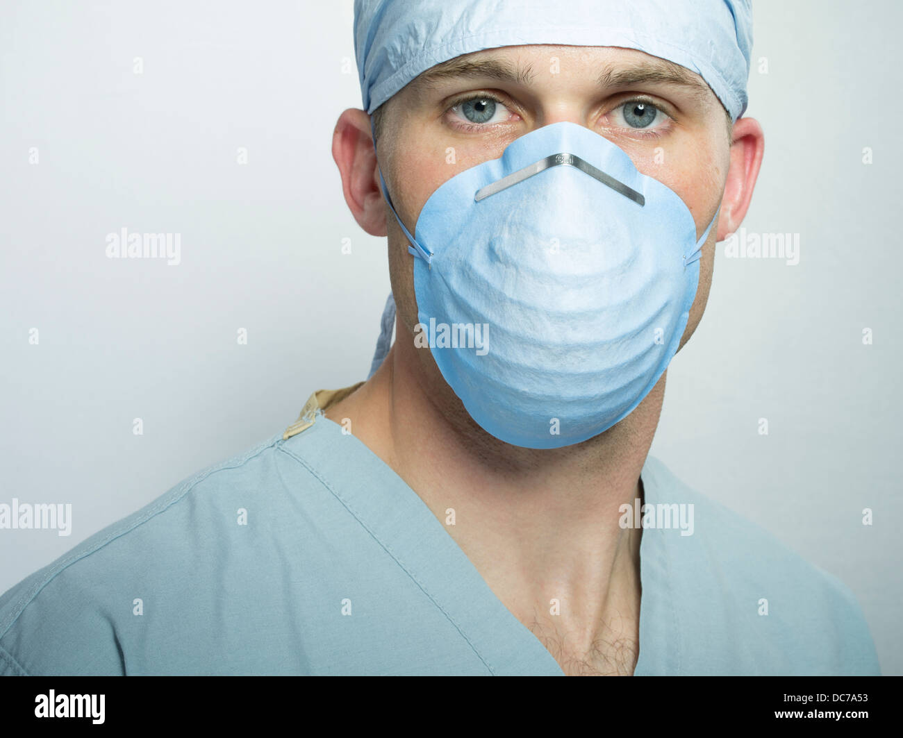 Male doctor / surgeon wearing hat, surgical scrubs and mask. Stock Photo