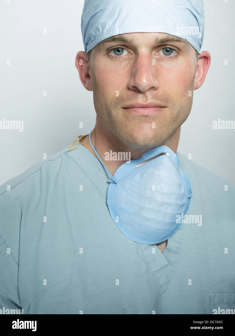 Male doctor / surgeon wearing hat, surgical scrubs and mask. Stock Photo