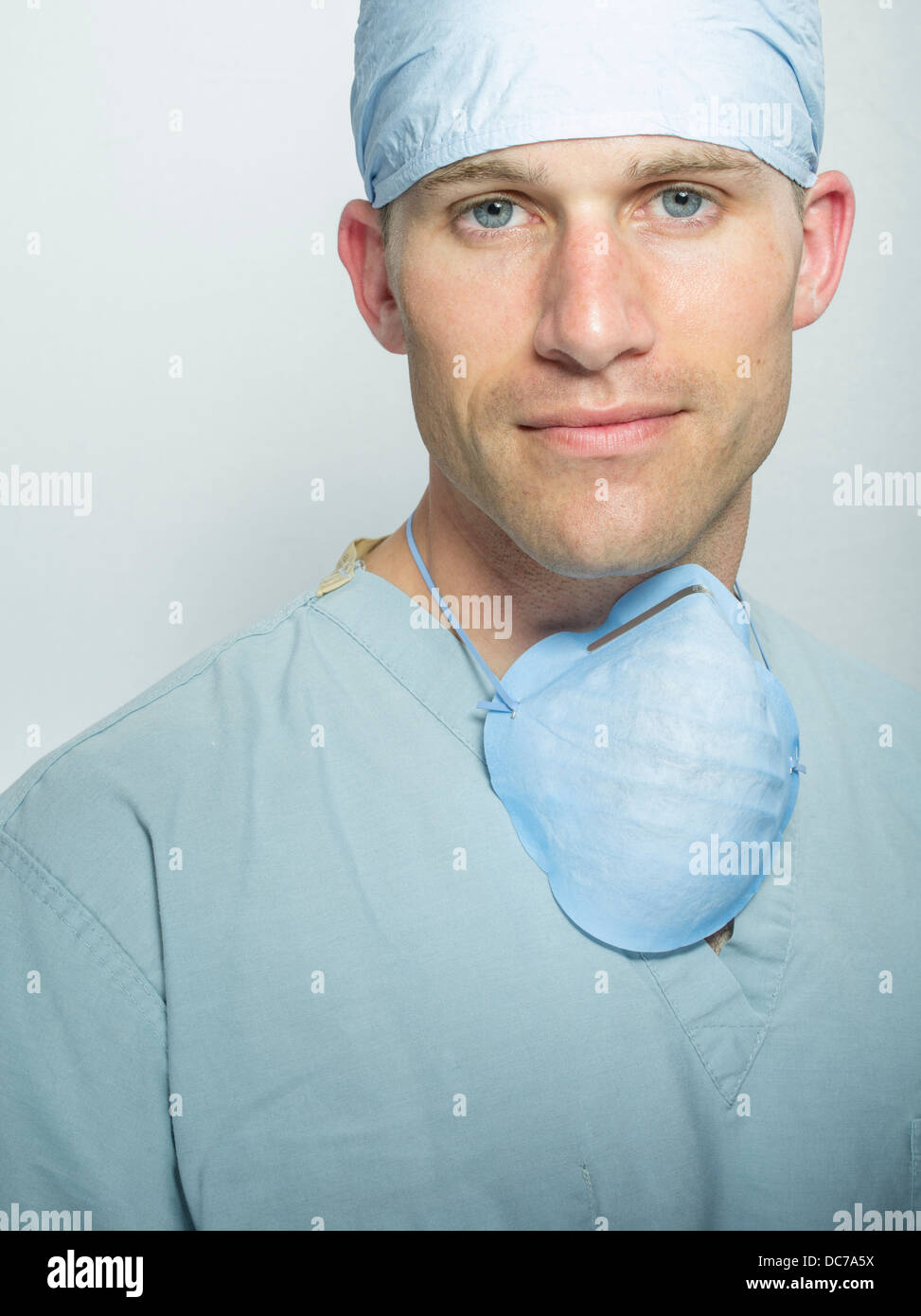 Male doctor / surgeon wearing hat, surgical scrubs and mask. Stock Photo