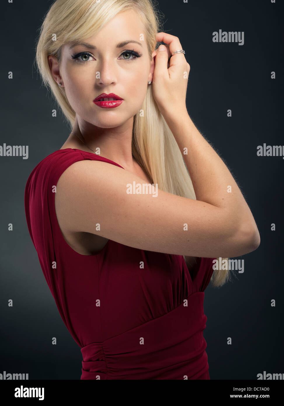Beautiful blond Caucasian woman in her twenties wearing deep red dress formal gown Stock Photo