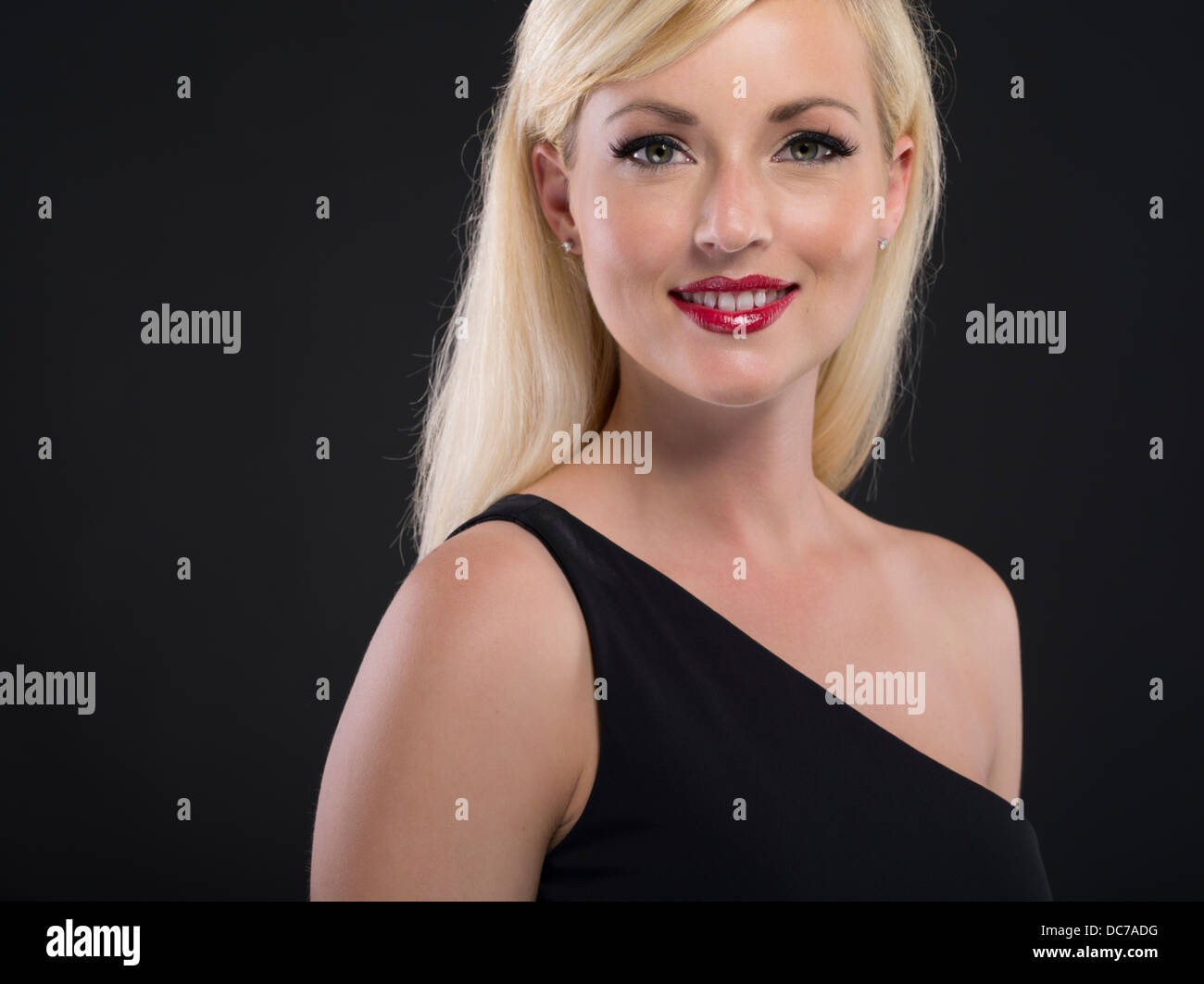 Beautiful blond Caucasian woman in her twenties wearing black asymmetrical one shoulder dress formal gown Stock Photo