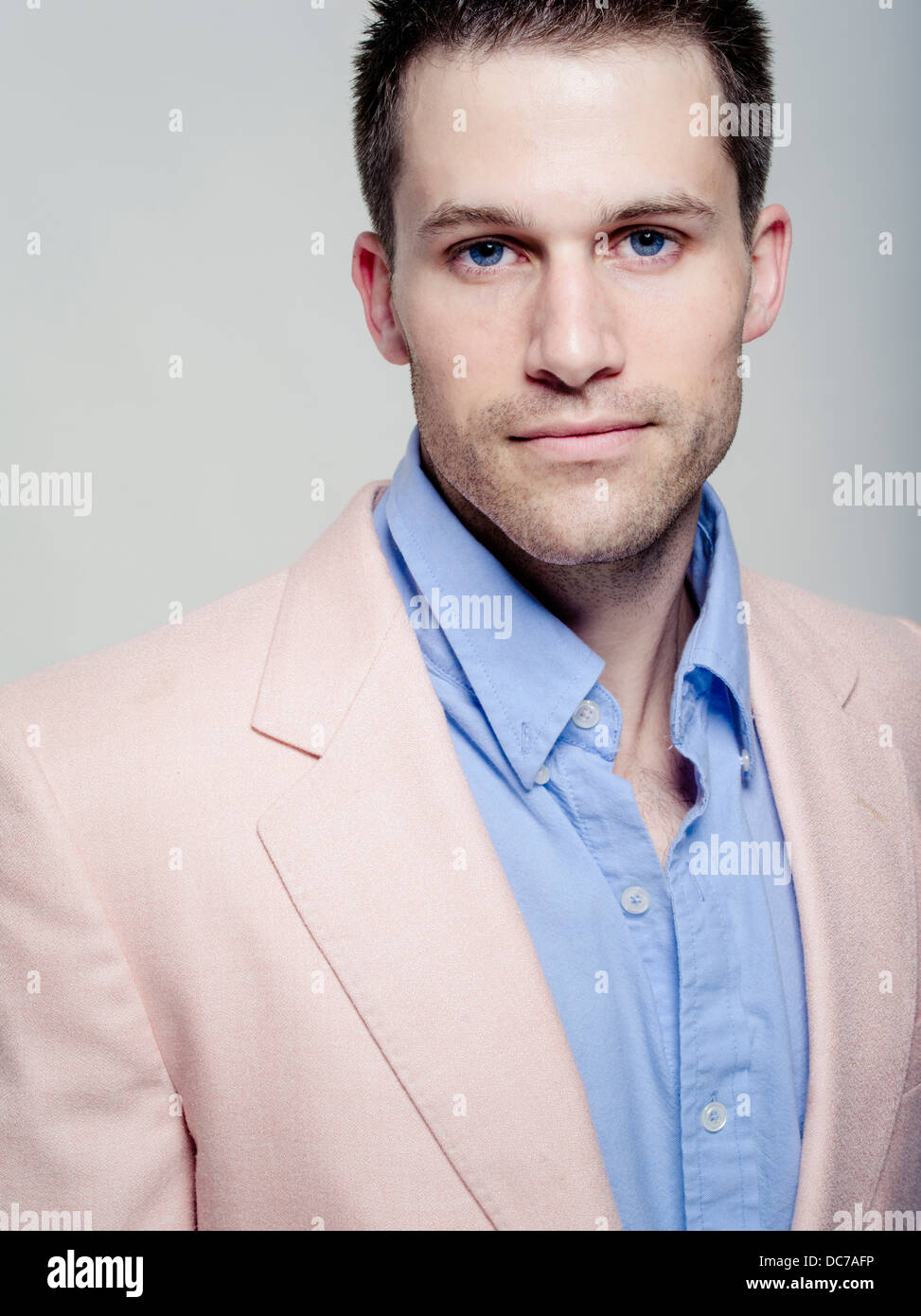 Handsome Caucasian man in his wearing baby blue shirt and pink jacket Stock Photo