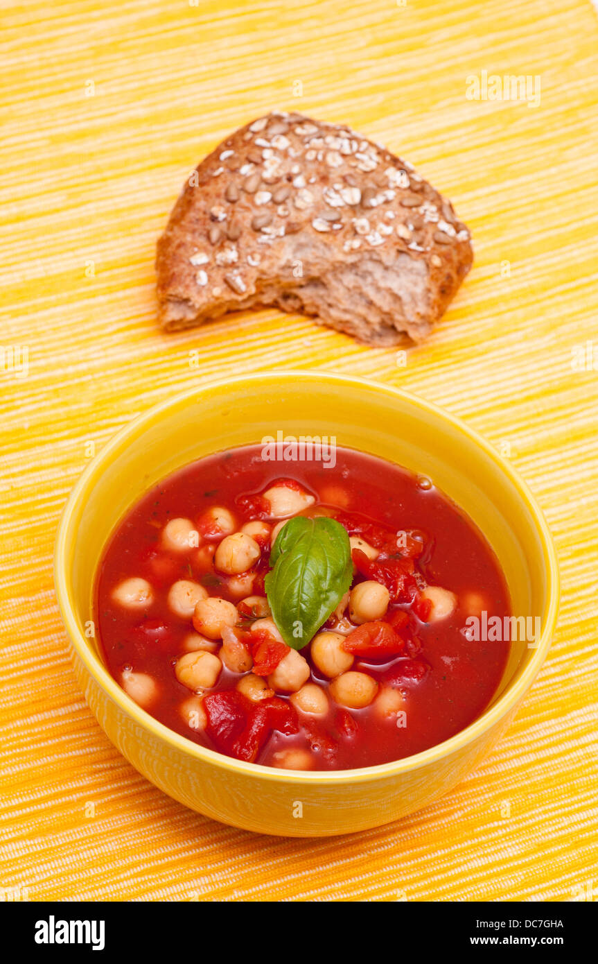 Bowl with soup of chick peas, tomatoes, basil and a roll Stock Photo Alamy