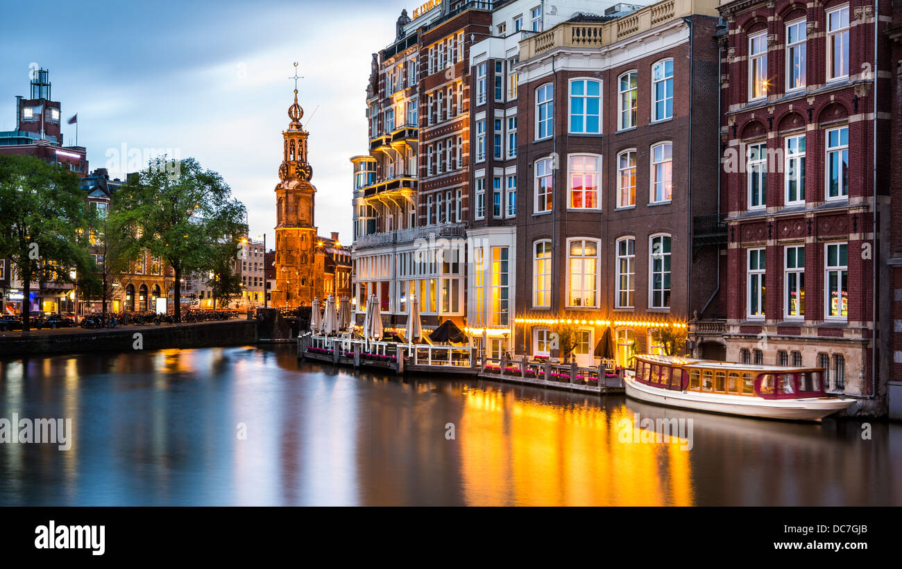 Amsterdam view at dusk, with typical dutch houses reflected in a canal and the Mint Tower landmark in the background Stock Photo