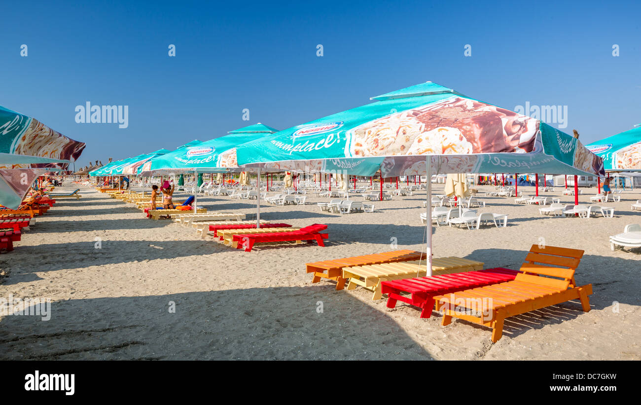 Row of colorful seabeds and umbrellas on a sandy beach Stock Photo