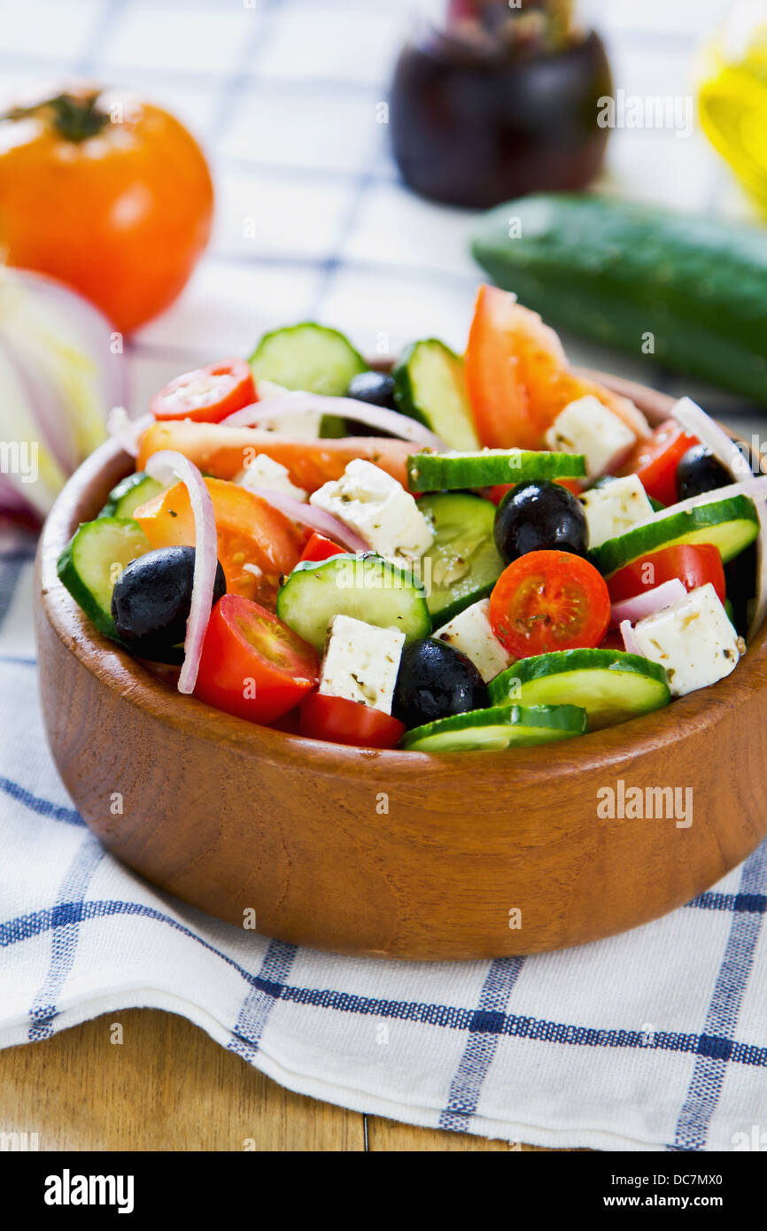 Greek salad in a wood bowl by fresh ingredients Stock Photo