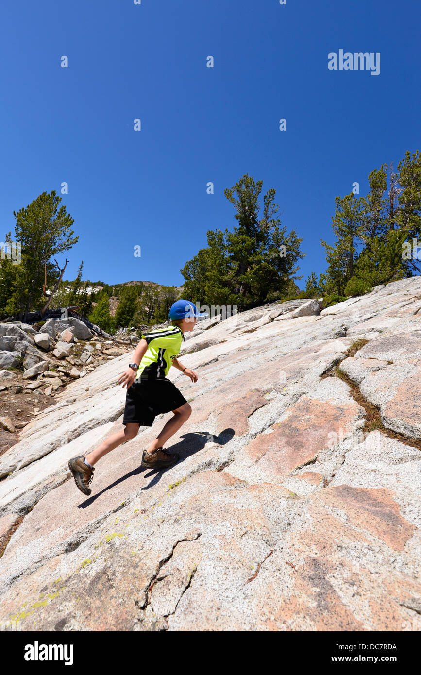 Boy running up a steep rock slope in the Wallowa Mountains, Oregon. Stock Photo
