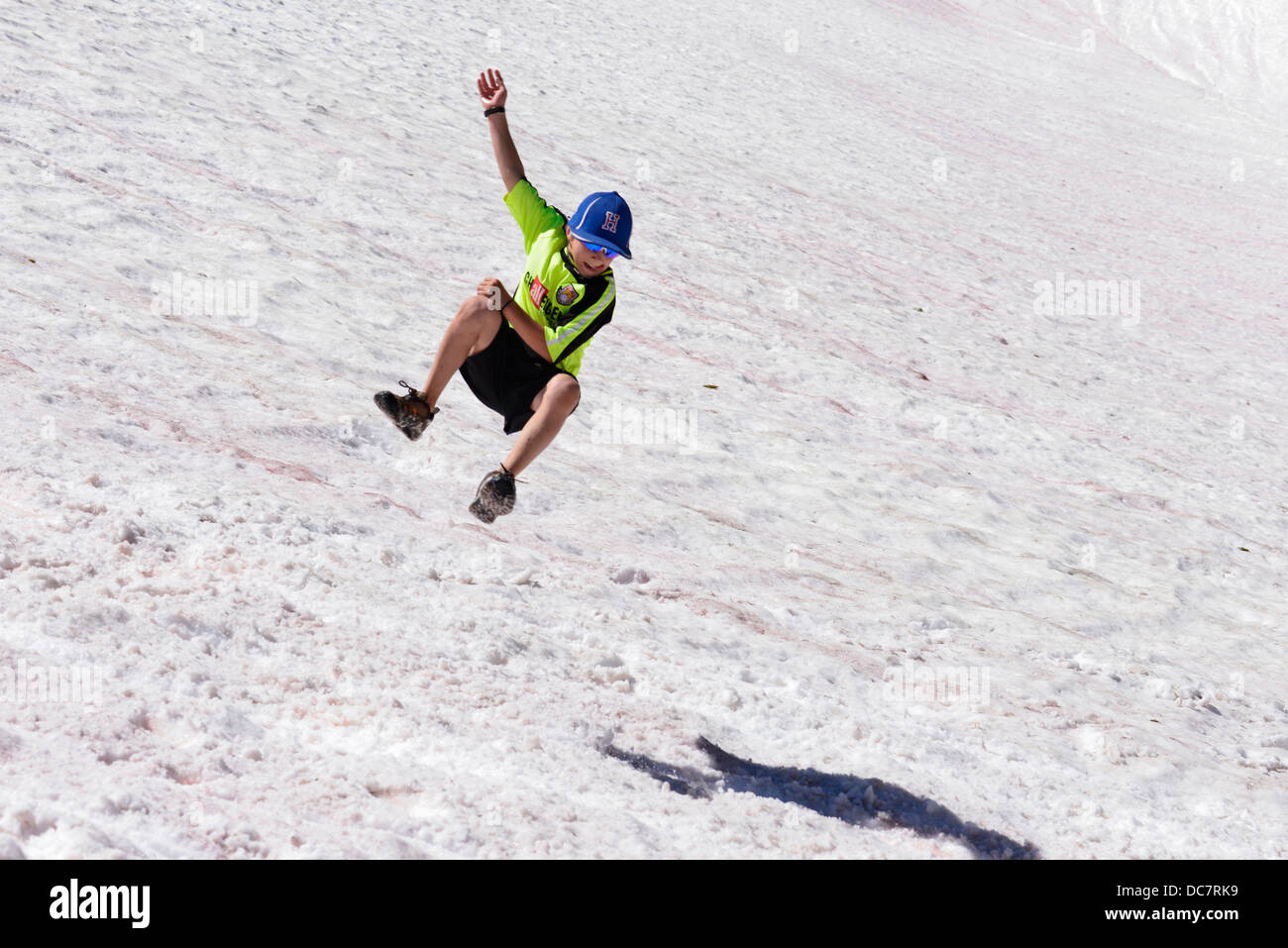 Boy catching air as he runs down a snowfield high in the Wallowa Mountains of Oregon. Stock Photo