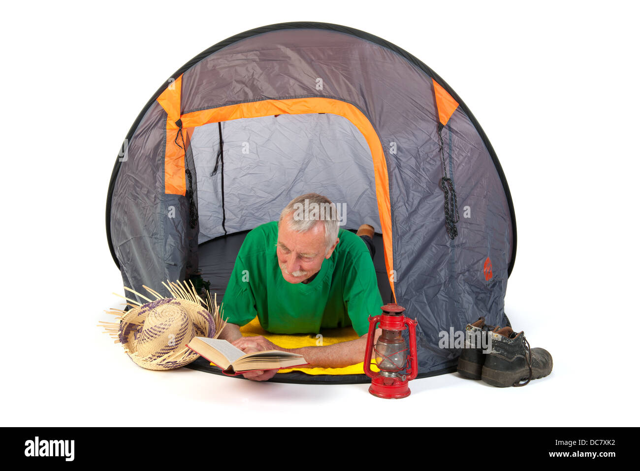 Senior man on vacation and reading laying in tent Stock Photo