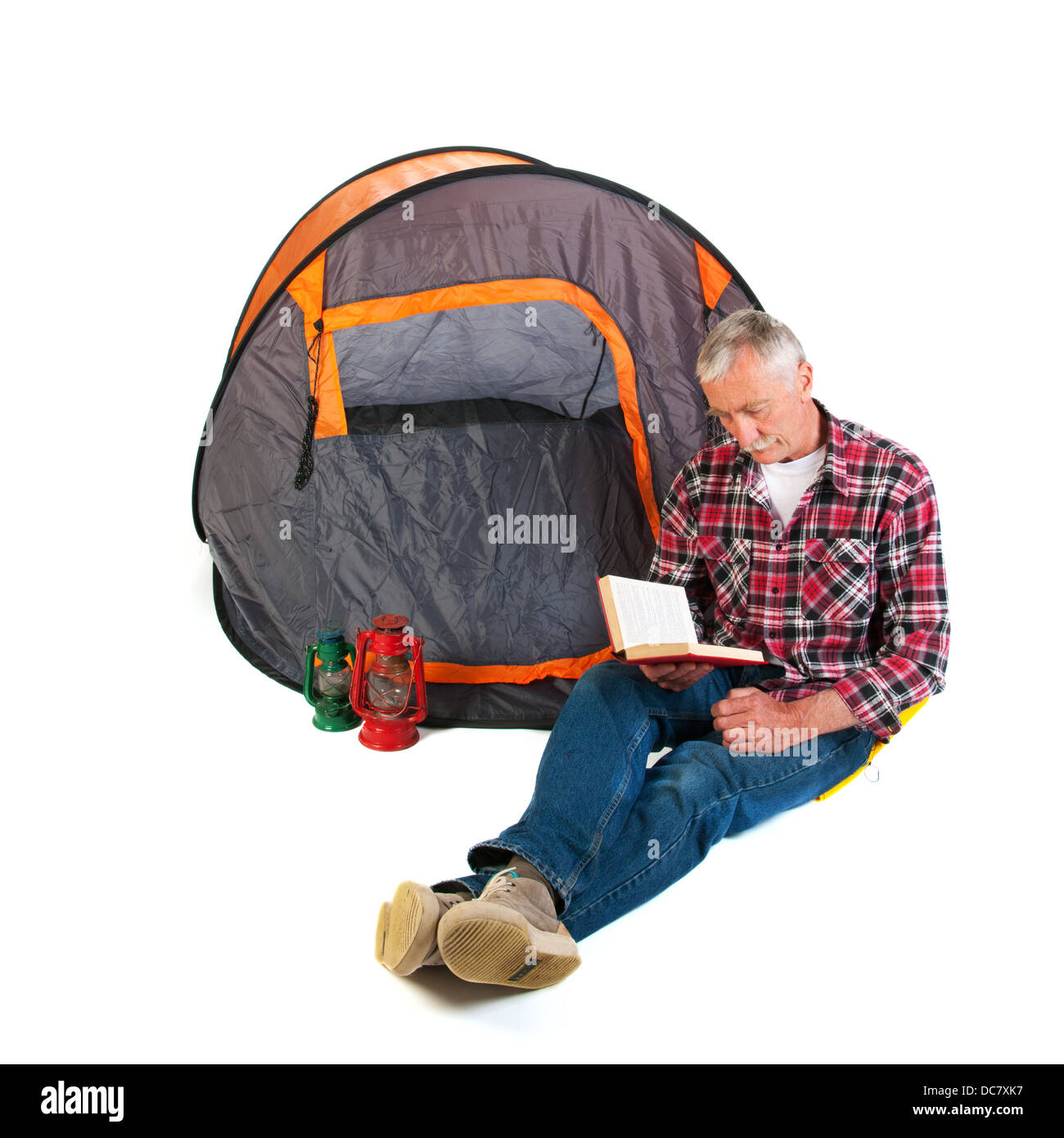 Senior man on vacation and reading by tent Stock Photo