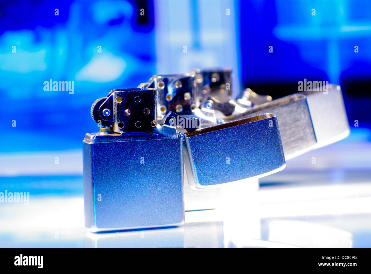 Three aluminium lighters in a row, with a cold blue background Stock