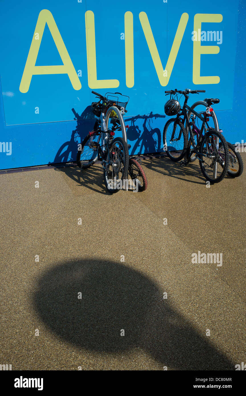 Bikes parked against wall with the word 'Alive' Stock Photo