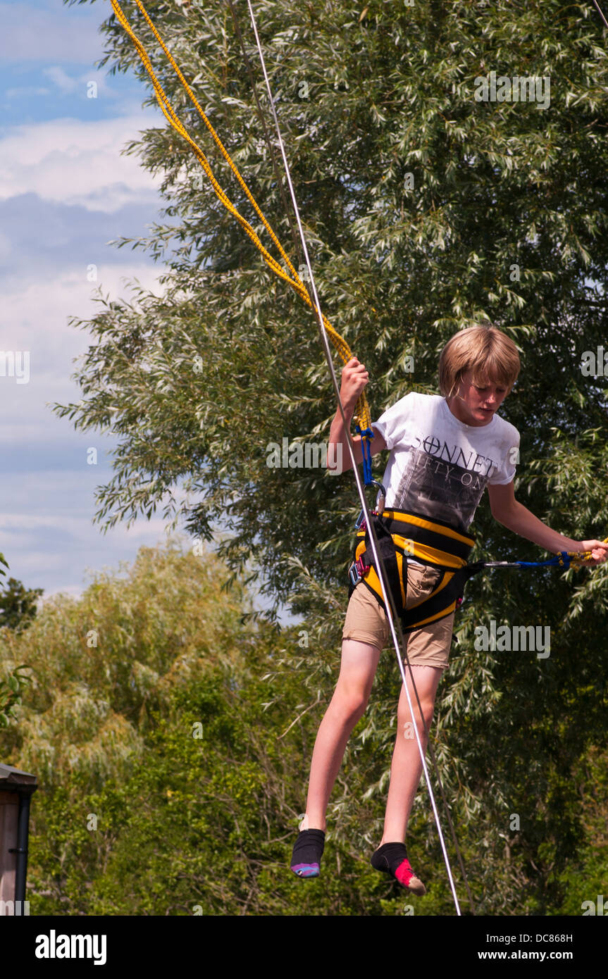 Young Boy Having Fun In The Sun Bouncing On Bungee Ropes Stock Photo
